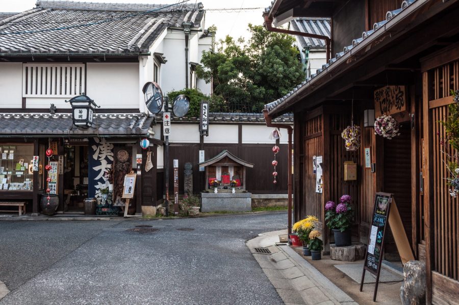 A street corner in Naramachi showing preserved merchant houses and a small wayside shrine (hokora).