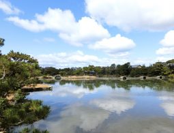 The large central pond (tidal pond) of Yosuien Garden, with arched stone bridges, reflecting the sky and surrounding trees.