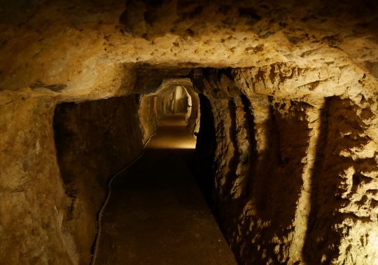 The interior of a dimly lit, hand-dug mine tunnel (mabu) at the Iwami Ginzan Silver Mine.