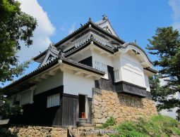 Close-up of one of the castle's turrets (yagura) with white walls and black wood, standing on a massive stone foundation.