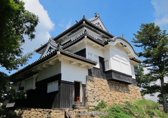 Close-up of one of the castle's turrets (yagura) with white walls and black wood, standing on a massive stone foundation.