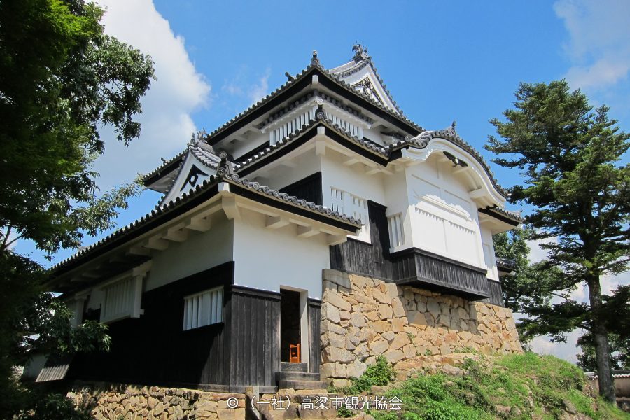 Close-up of one of the castle's turrets (yagura) with white walls and black wood, standing on a massive stone foundation.
