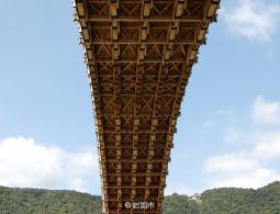 An extreme low-angle view from the river up into the complex wooden structure and joinery beneath one of the Kintai Bridge arches.