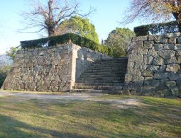 A stone staircase leading up through two tall stone walls, part of the castle's fortified entrance or defense structure.