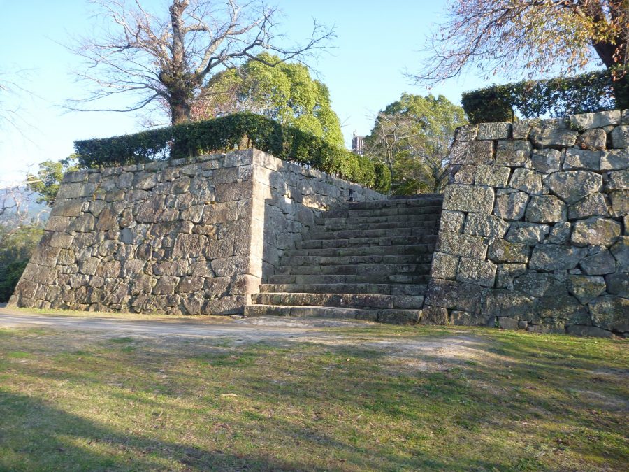 A stone staircase leading up through two tall stone walls, part of the castle's fortified entrance or defense structure.