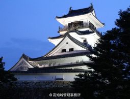 Kochi Castle keep illuminated at dusk against a deep blue sky.