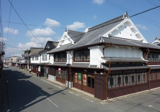 The preserved streetscape of Yame Fukushima, showing two-story traditional merchant houses with white plaster walls and tiled roofs.