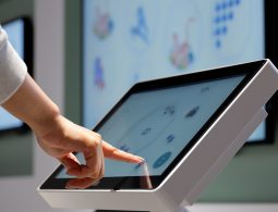 A hand using a touchscreen interactive display to browse digital content at the museum.