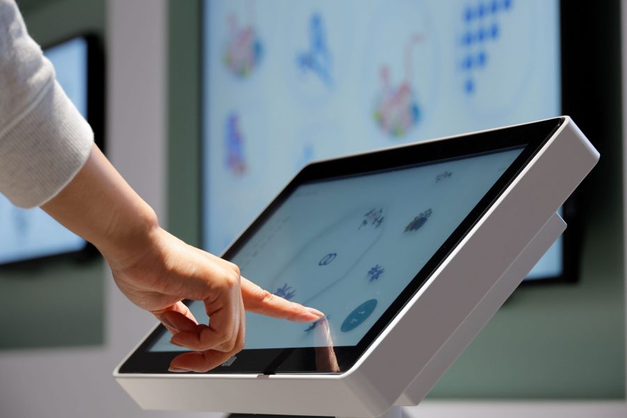 A hand using a touchscreen interactive display to browse digital content at the museum.