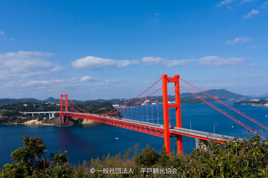 The long, red Hirado suspension bridge spanning the blue water between Hirado Island and the mainland.