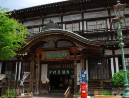 The main entrance facade of Takegawara Onsen, featuring traditional Japanese wooden architecture, like its curved karahafu gable roof.