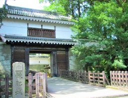 The reconstructed main gate (likely Otemon) of Obi Castle, featuring white walls, a wooden turret, and a stone pillar with Japanese characters.