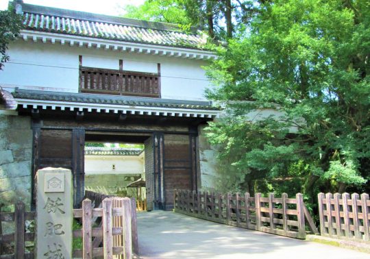 The reconstructed main gate (likely Otemon) of Obi Castle, featuring white walls, a wooden turret, and a stone pillar with Japanese characters.