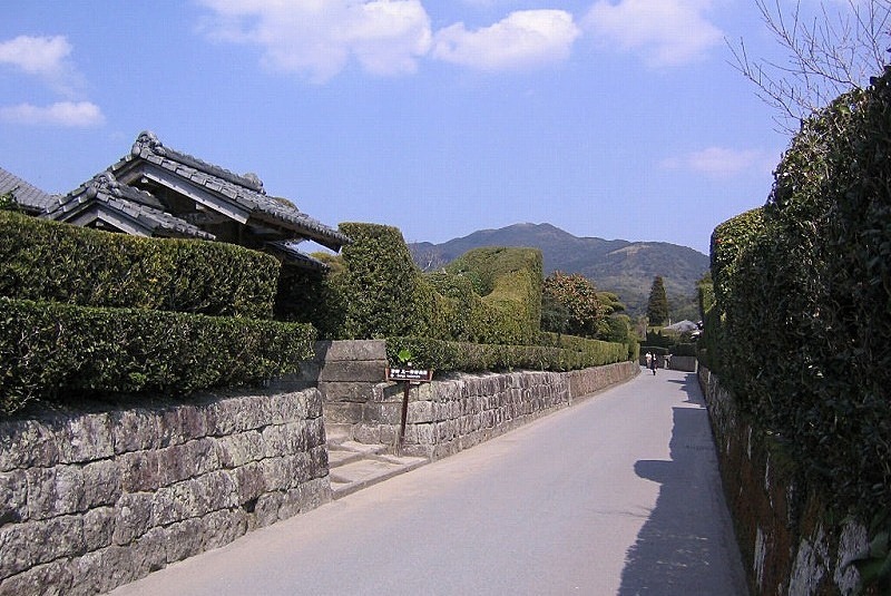 The historic street of the Chiran Samurai Residences, lined with low stone walls and manicured boxwood hedges.