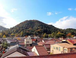 View of Mount Utsubuki with autumn foliage, rising above the traditional tiled rooftops of Kurayoshi city in Tottori Prefecture.