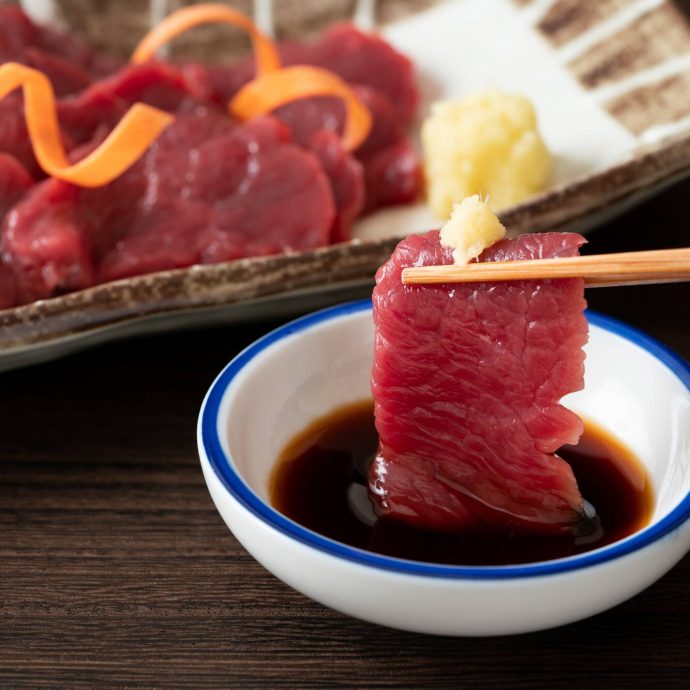 Basashi (horse sashimi) dipped in soy sauce.