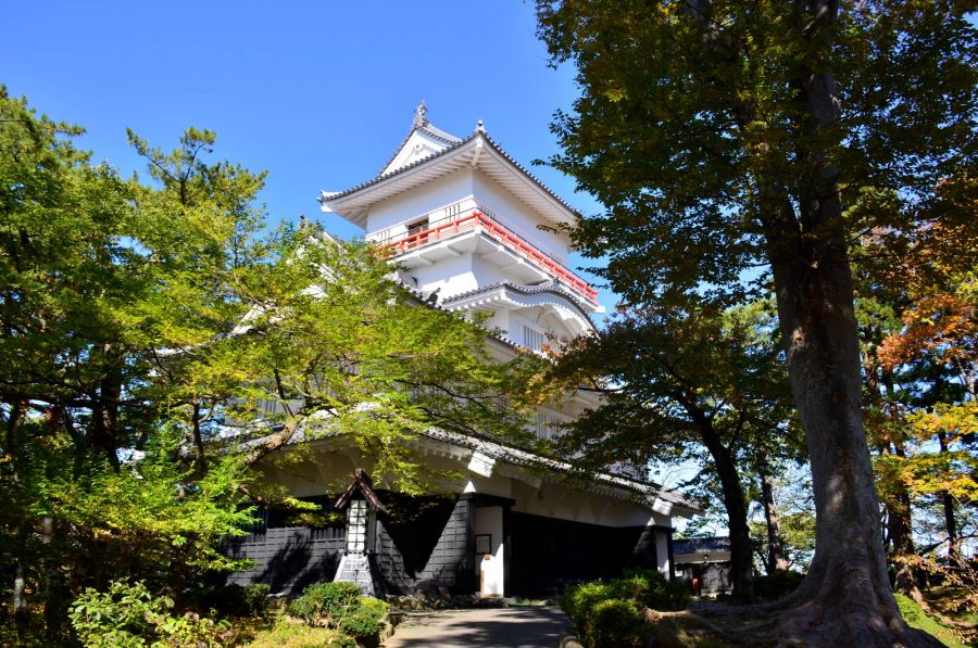 Japanese castle tower surrounded by trees.