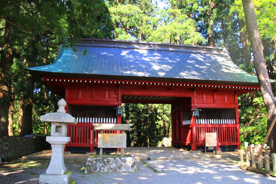 Red shrine gate with green trees in the background.