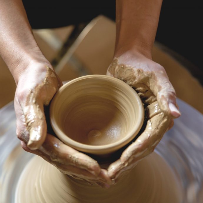 Potter's hands shaping clay on a pottery wheel.