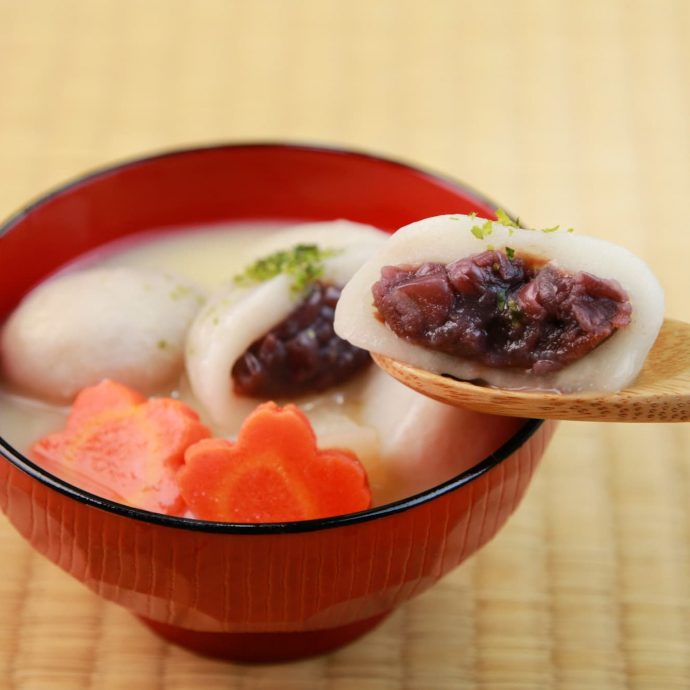 Anmochi zoni (sweet mochi soup) in a red bowl.