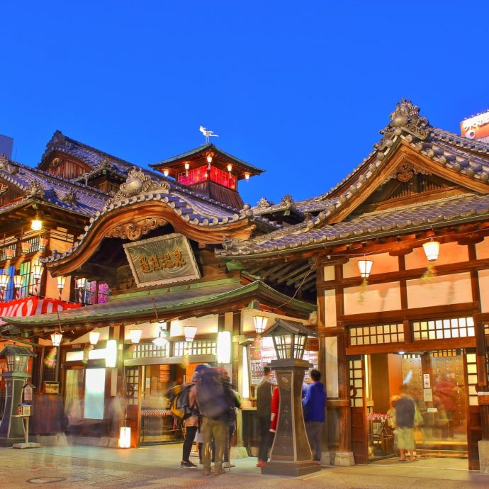 Dogo Onsen main building illuminated at night.