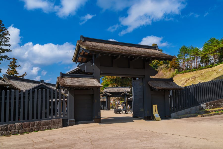 View of the black wooden gate and fences of the reconstructed Hakone Checkpoint under a blue sky.