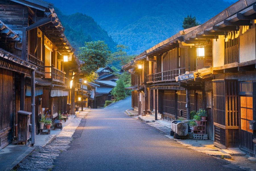 Evening street view of Tsumago-juku post town featuring traditional wooden buildings and glowing lanterns.