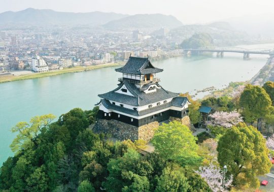 Inuyama Castle standing on a hilltop overlooking a river and the city.