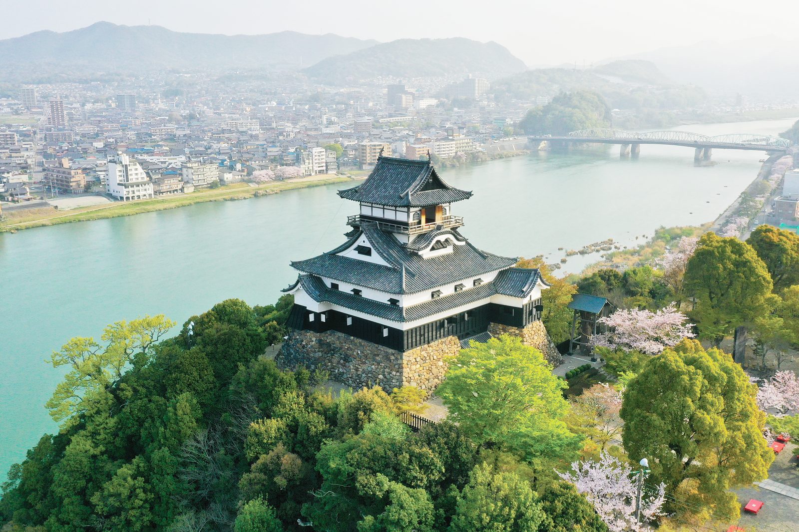 Inuyama Castle standing on a hilltop overlooking a river and the city.