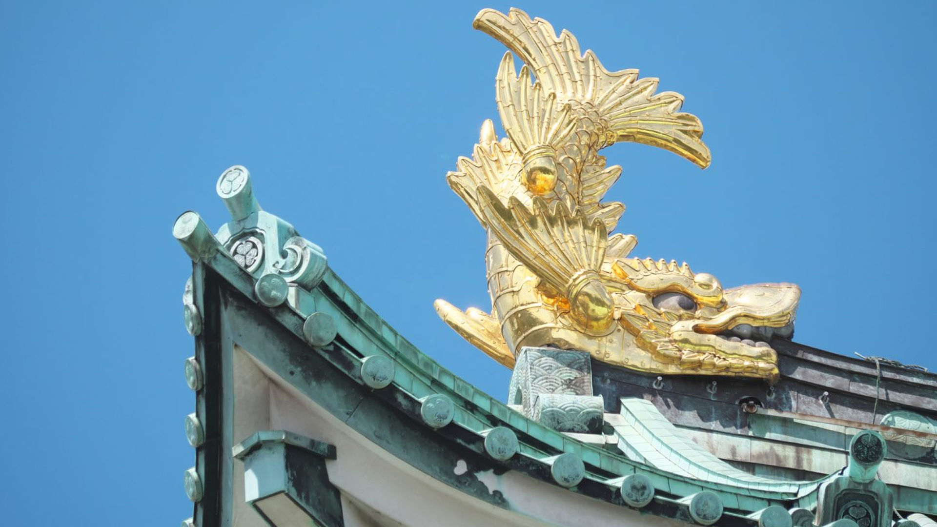 Close-up of a golden Shachihoko ornament on the green roof of Nagoya Castle.